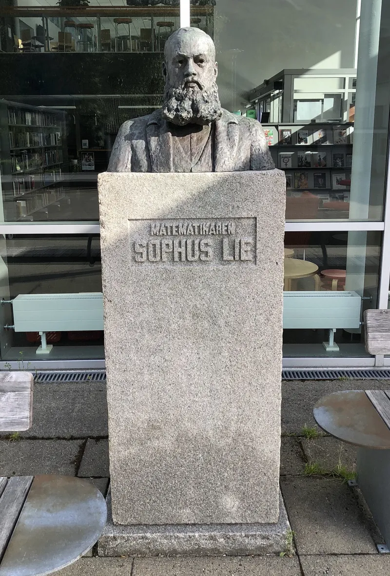 Hoher Gedenkstein mit Inschrift in einer Grünanlage