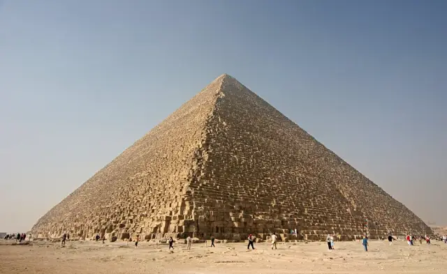 Die Cheops-Pyramide in Gizeh vor blauem Himmel, im Vordergrund Wüstensand