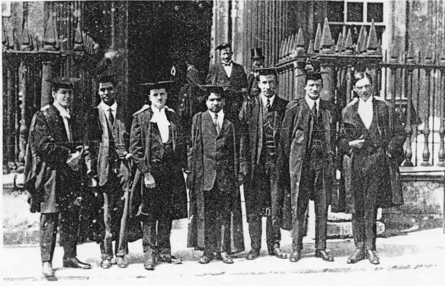 Schwarz-Weiß-Foto einer Gruppe von Männern in akademischen Roben vor einem Gitterzaun, in der Mitte Ramanujan
