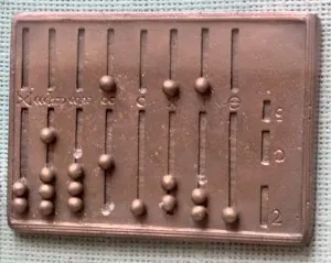 Nachbau eines römischen Hand-Abakus aus Metall mit senkrechten Schlitzen und kleinen Kugeln